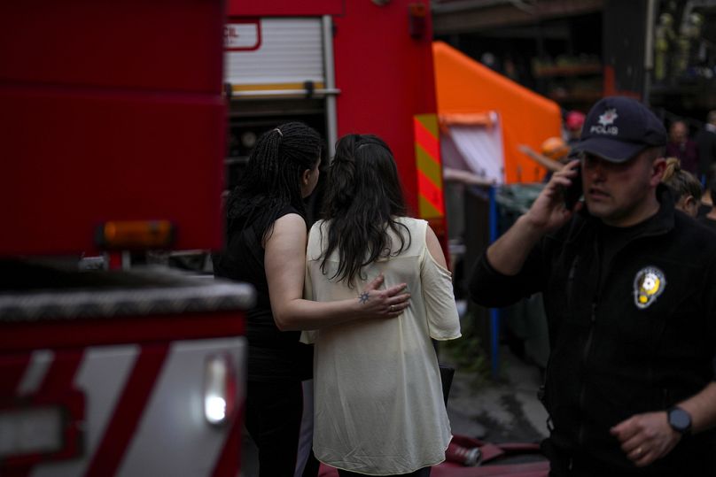 Two women gather as firefighters and emergency teams work in the aftermath of a fire in a nightclub in Istanbul, Turkey, Tuesday, April 2, 2024