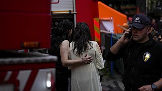 Zwei Frauen stehen mit Rettungskräften nach einem Brand in einem Nachtclub in Istanbul, Türkei, der ohne Genehmigung renoviert wurde und mindestens 29 Tote forderte, 2.4.2024.