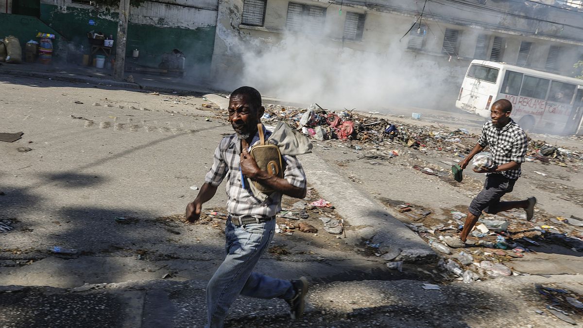  Un homme courre se cacher alors que la police anti-émeute lance des gaz lacrymogènes pour tenter de disperser les gens près du Palais National, à Port-au-Prince, à Haïti, le 