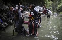 Migrantes haitianos caminan por el agua mientras cruzan el Tapón del Darién desde Colombia a Panamá con la esperanza de llegar a Estados Unidos, el 9 de mayo de 2023.