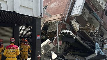 In this photo released by the National Fire Agency, members of a search and rescue team prepare outside a leaning building in the aftermath of an earthquake in Hualien.