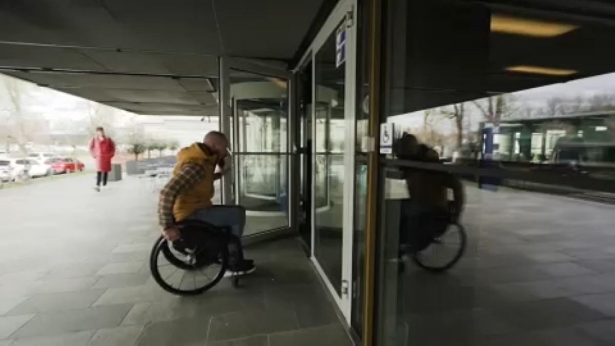 Man in yellow vest in a wheelchair entering a building