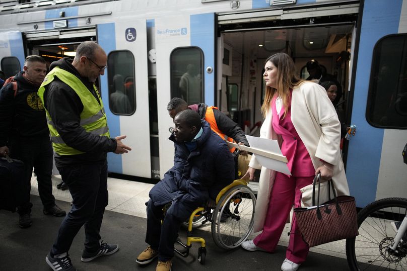 ARCHIVO - Babou Sene es ayudado a bajar de un tren el miércoles 26 de abril de 2023 en la estación de tren Gare de Lyon, en París.