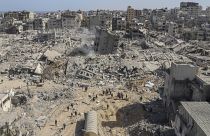 فلسطينيون يتجولون بين آثار الدمار الذي خلفه الهجوم الجوي والبري الإسرائيلي على قطاع غزة بالقرب من مستشفى الشفاء في مدينة غزة، الاثنين، 1 أبريل/نيسان 2024