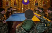 سربازان اوکراینی پرچم کشورشان را قبل از گذاشتن بر روی تابوت یک سرباز کشته شده در دست دارند. کی‌یف، اوکراین، سه شنبه، ۲۶ مارس ۲۰۲۴.