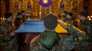 سربازان اوکراینی پرچم کشورشان را قبل از گذاشتن بر روی تابوت یک سرباز کشته شده در دست دارند. کی‌یف، اوکراین، سه شنبه، ۲۶ مارس ۲۰۲۴.
