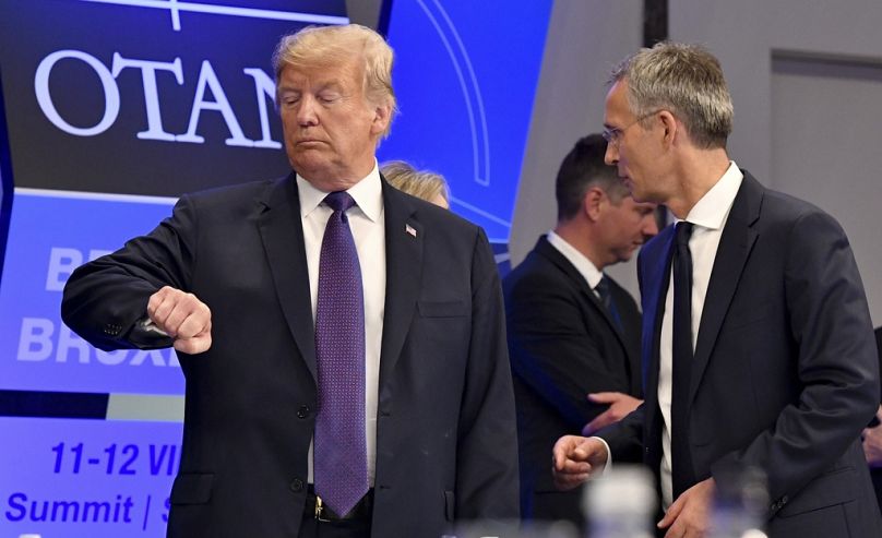 U.S. President Donald Trump checks his watch as NATO Secretary General Jens Stoltenberg stands beside him in Brussels, July 2018