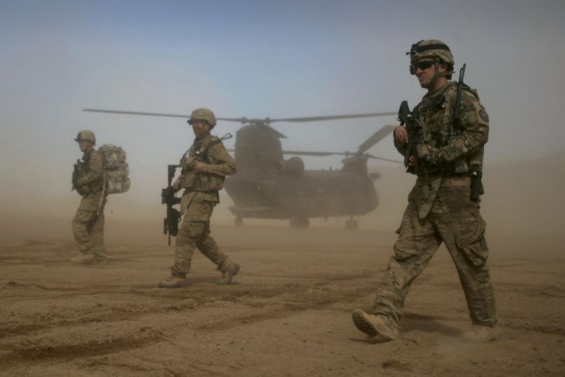 Soldiers of the NATO- led International Security Assistance Force (ISAF), walk as a Chinook helicopter is seen on the back ground in Shindand, Herat, January 2012