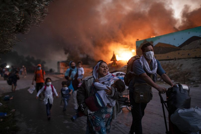 ARCHIVO - En esta foto de archivo del miércoles 9 de septiembre de 2020, refugiados y migrantes huyen de un incendio en el campamento de Moria, en la isla griega de Lesbos