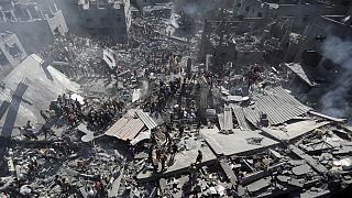 Palestinesi ispezionano le macerie degli edifici distrutti dopo gli attacchi aerei israeliani sulla città di Khan Younis, nel sud della Striscia di Gaza, il 26 ottobre 2023 