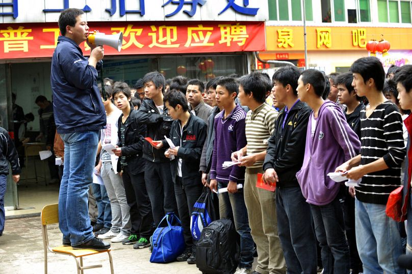 A recruiter from Foxconn talks to job applicants outside the factory in Shenzhen in southern China's Guangdong province, February 2010