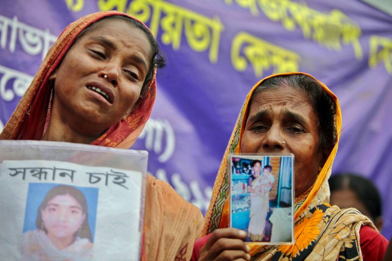 Bangladeshi mothers cry for their missing ones while holding their photos at the site of the collapsed Rana Plaza building in Savar near Dhaka, August 2013