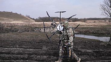 un soldato russo trasporta un drone ucraino catturato, restaurato e ammodernato dall'esercito in una località non rivelata dell'Ucraina