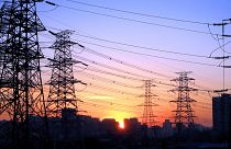 Die Sonne geht zwischen Stromleitungen in Peking, China, unter.