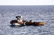 Сотрудники береговой охраны Италии готовятся к буксировке лодок, перевозящих мигрантов