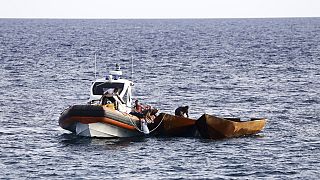 A parti őrség munkatársai migránsokat szállító csónakok vontatására készülnek a dél-olaszországi Lampedusa szicíliai szigetének kikötője közelében