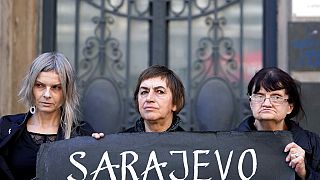 Members of the anti-war organization "Women in Black" hold a banner marking the 30th anniversary of the start of the siege of the Bosnian capital, Sarajevo