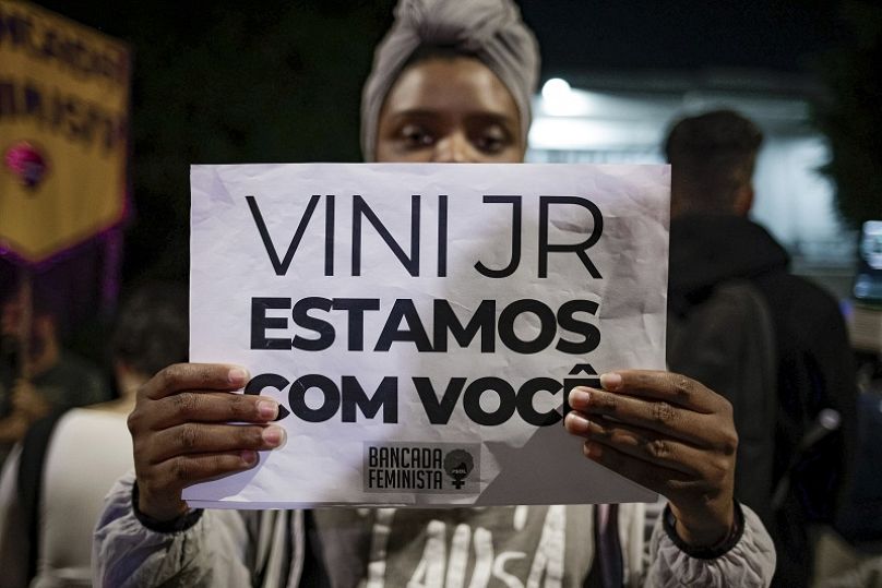 Una mujer sostiene un cartel en apoyo a Vinicius Junior