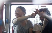 Climate activist Greta Thunberg flashes a V-sign after being detained and driven off in a bus after joining protestors who blocked a road during a climate protest