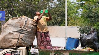 Eine Müllsammlerin löscht ihren Durst, während sie an einem heißen Tag in Hyderabad, Indien, am 12. März 2024 auf einem Lastwagen steht.