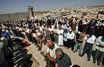 مصلون فلسطينيون يصلون خلف المتاريس عند حاجز قلنديا بين مدينة رام الله بالضفة الغربية والقدس
