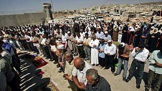مصلون فلسطينيون يصلون خلف المتاريس عند حاجز قلنديا بين مدينة رام الله بالضفة الغربية والقدس