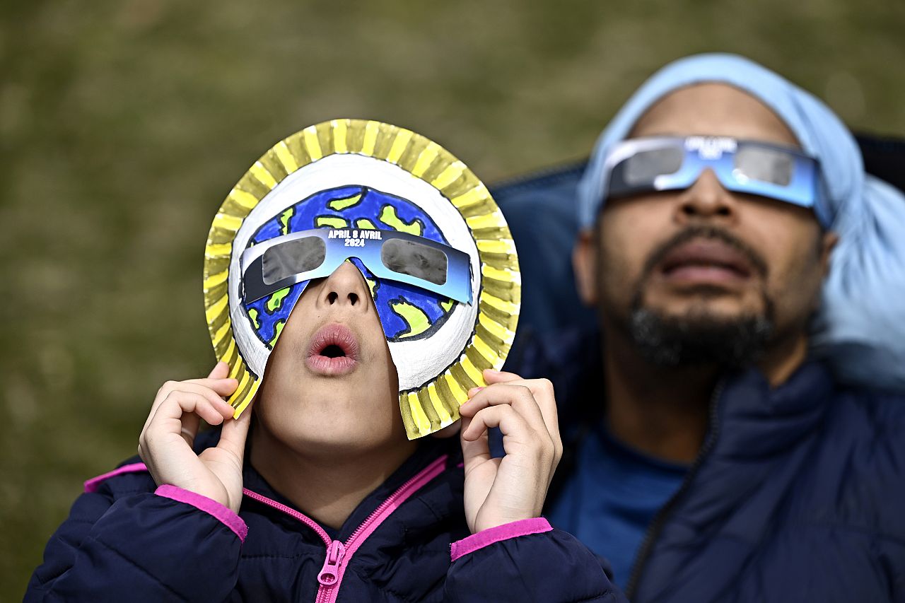 Dezaray Butts and her father Douglas wear solar eclipse glasses as they observe the partial phase of a total solar eclipse.