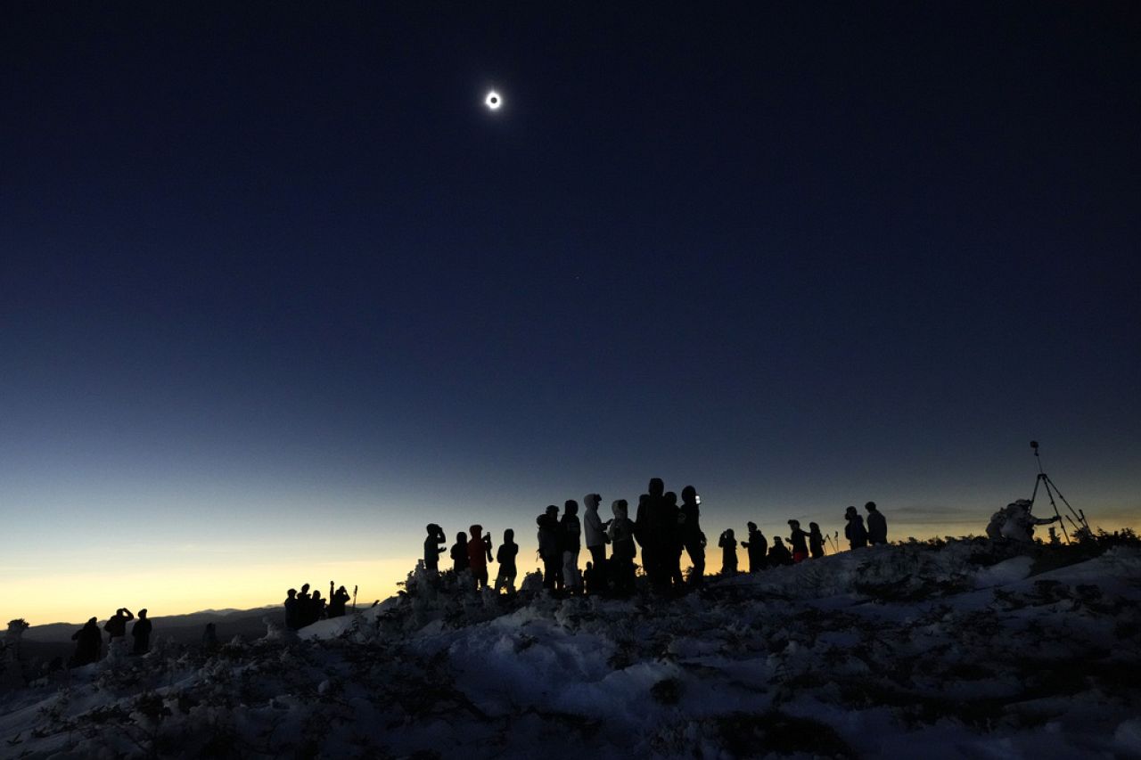 Skiers and hikers take in the view from the Appalachian Trail at the summit of Saddleback Mountain during the total solar eclipse, Monday, April 8, 2024