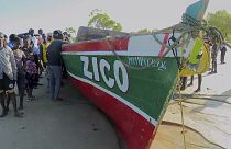 Captura de vídeo de Television Mozambique, que muestra a un grupo junto al barco que, según los medios locales, naufragó el domingo frente a la costa norte de Mozambique