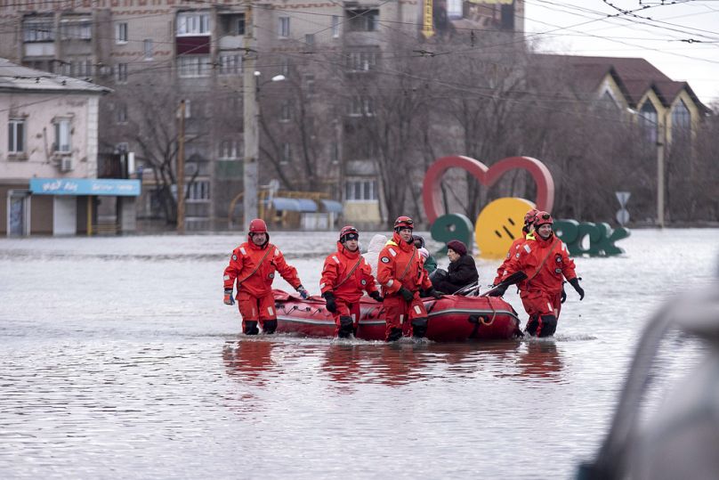 Emergency workers use a boat to evacuate local residents in a flooded street after a part of a dam burst, in Orsk, Russia on Monday, April 8, 2024.