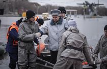 I soccorritori aiutano una donna a scendere da una barca durante l'evacuazione dei residenti in una strada allagata dopo gli allagamenti, a Orsk, in Russia, 8/04/2024