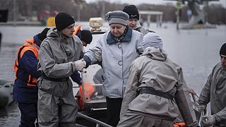Emergency workers assist a woman to deboard a boat during evacuations local residents in a flooded street after a part of a dam burst, in Orsk, Russia on Monday, April 8, 2024