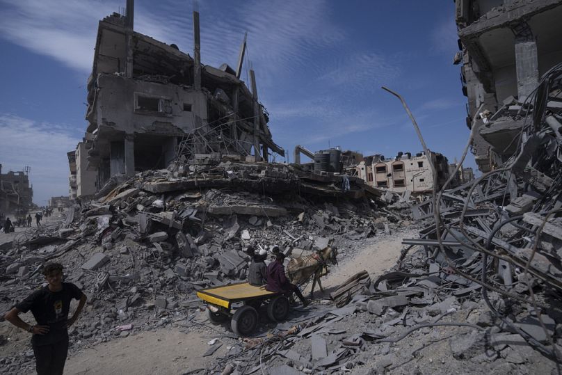 Palestinians walk through the destruction in the wake of an Israeli air and ground offensive in Khan Younis, southern Gaza Strip, Monday, April 8, 2024.