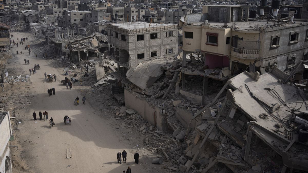 Palestinians walk through the destruction in the wake of an Israeli air and ground offensive in Khan Younis, southern Gaza Strip, Monday, April 8, 2024.