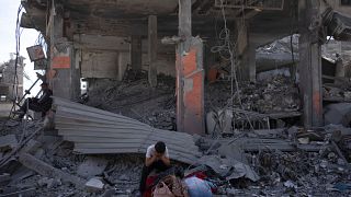 فلسطينيان يجلسان على أنقاض منزل مدمر في خان يونس. 2024/04/08
