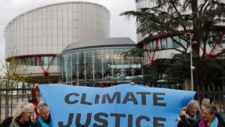 AİHM binası önünde İklim Adaleti yazılı bir pankart açan iklim aktivistleri