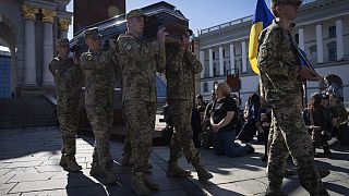 Ljudi kleče dok vojnici nose lijesove ukrajinskih vojnika tijekom pogrebne ceremonije na Trgu neovisnosti u Kijevu, Ukrajina, utorak, 9. travnja 2024.