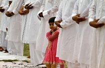 A Muslim girl looks on as elders offer prayers during Eid al-Fitr in Allahabad, India