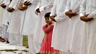 A Muslim girl looks on as elders offer prayers during Eid al-Fitr in Allahabad, India