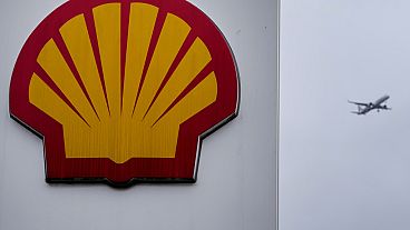 An aircraft passes a sign at a shell petrol station in London, Thursday, Feb. 2, 2023.