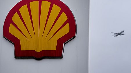 An aircraft passes a sign at a shell petrol station in London, Thursday, Feb. 2, 2023.