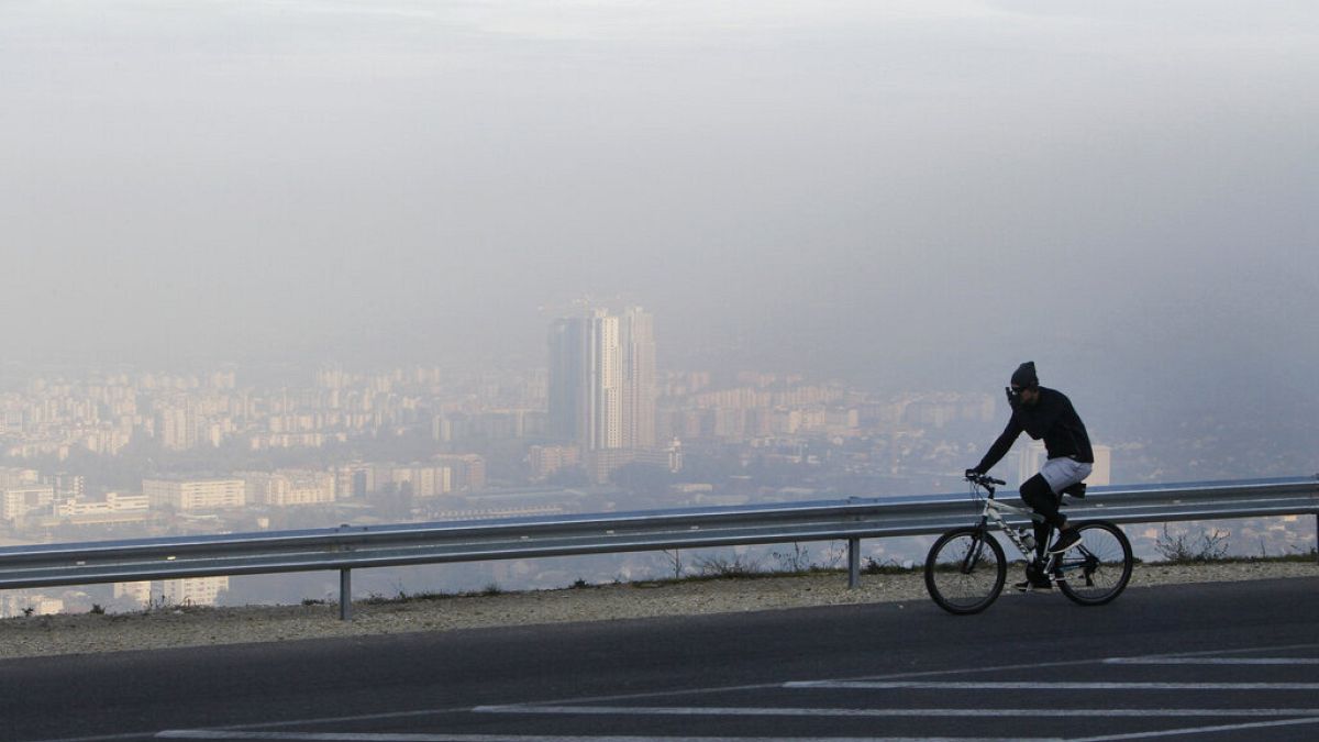 رجل يركب دراجة على طول طريق على جبل فودنو، مع رؤية بلدة سكوبجيس، العاصمة المقدونية، من خلال الهواء الملوث في الخلفية، الأحد، 8 نوفمبر 2015. 