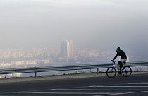 A man rides a bicycle along a road on the Vodno Mountain, with the town of Skopjes the Macedonian capital seen through polluted air in the background, Sunday, Nov. 8, 2015. 