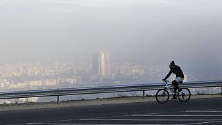 رجل يركب دراجة على طول طريق على جبل فودنو، مع رؤية بلدة سكوبجيس، العاصمة المقدونية، من خلال الهواء الملوث في الخلفية، الأحد، 8 نوفمبر 2015. 