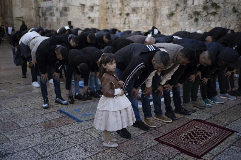 A girl stands next to her relative during the Eid al-Fitr prayers outside of the Al-Aqsa Mosque compound in the Jerusalem's Old City, Wednesday, April 10, 2024.