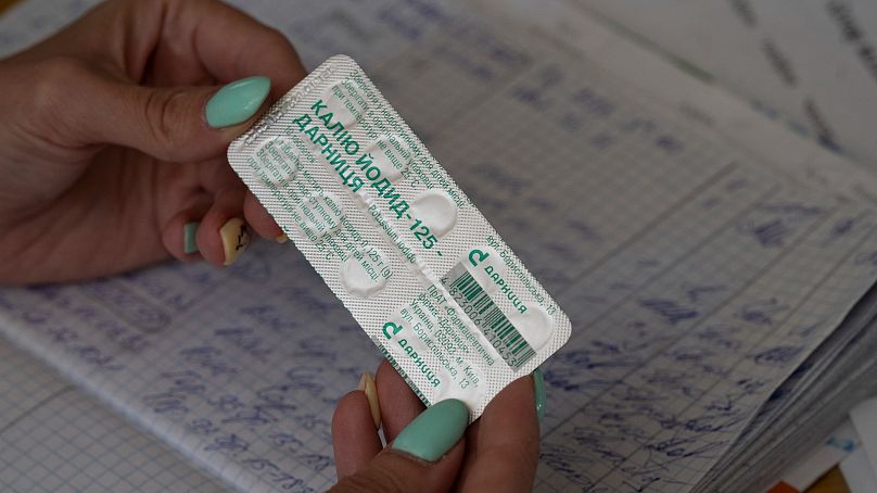 Uma mulher mostra um pacote de comprimidos de iodo antes de os distribuir aos residentes de uma escola em caso de fuga de radiação em Zaporíjia, Ucrânia, 2 de setembro de 2