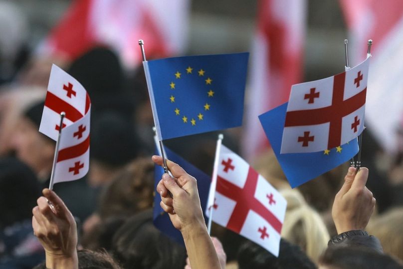 Georgians wave EU and national flags as they gather to celebrate Georgia's EU candidacy at Liberty Square in Tbilisi, December 2023