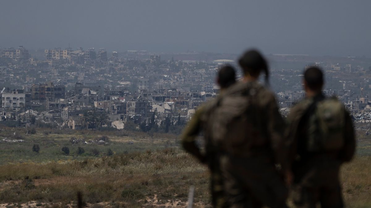 جنود إسرائيليون يقفون بالقرب من الحدود بين إسرائيل وغزة وينظرون إلى المباني المدمرة في القطاع