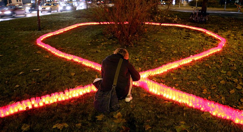 Un hombre enfrente de un lazo simbólico contra SIDA, Alemania, Nov. 30, 2006.