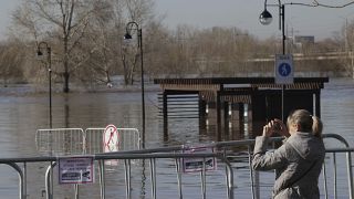 A woman takes a photo of a flooded area next to Ural river in Orenburg, Russia.